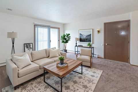 A living room with a beige couch, a wooden coffee table, and a rug with a floral pattern.