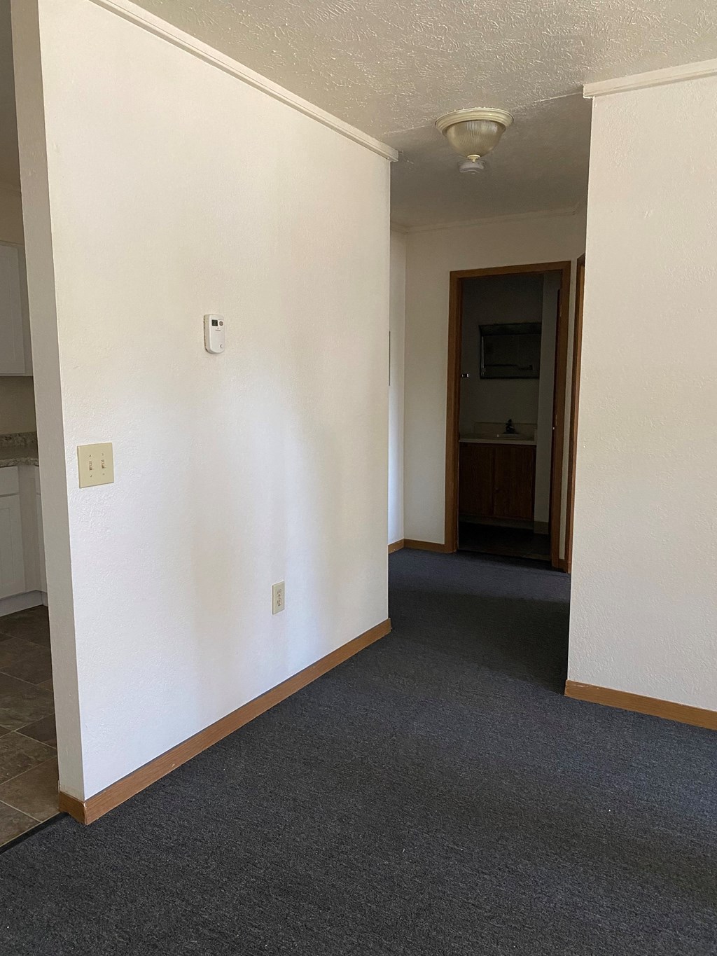 an empty room with a hallway and a door to a bathroom