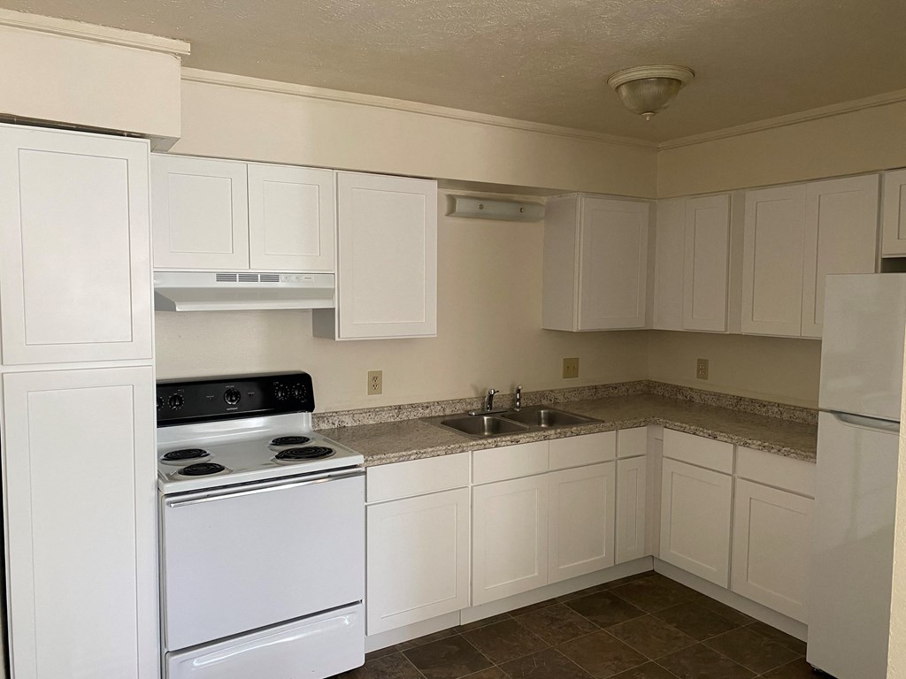 an empty kitchen with white appliances and white cabinets