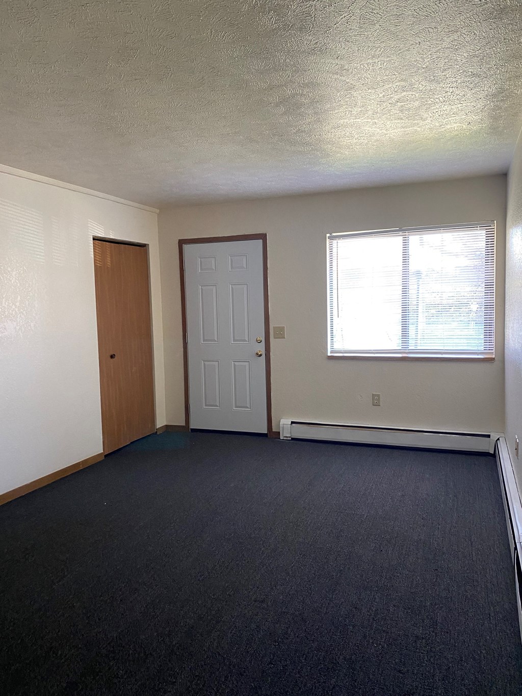 an empty living room with a door and a window