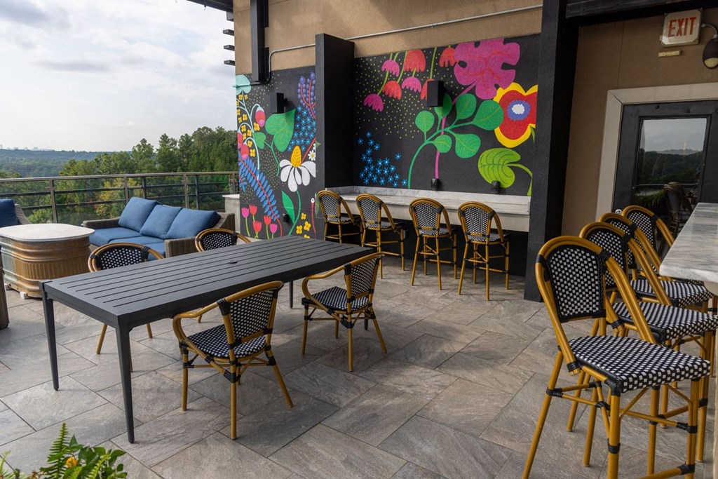 a patio with tables and chairs and a mural on the wall