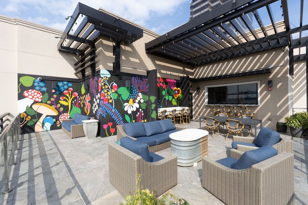 a patio with couches and tables and a mural on the wall