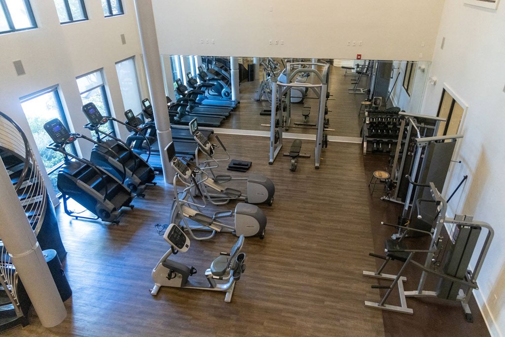 a gym with cardio machines and weights on a wood floor