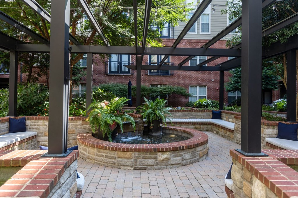 a courtyard with a fountain and a brick wall