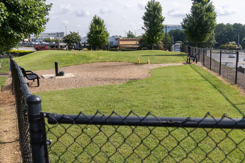 a park with a dirt field and a fence