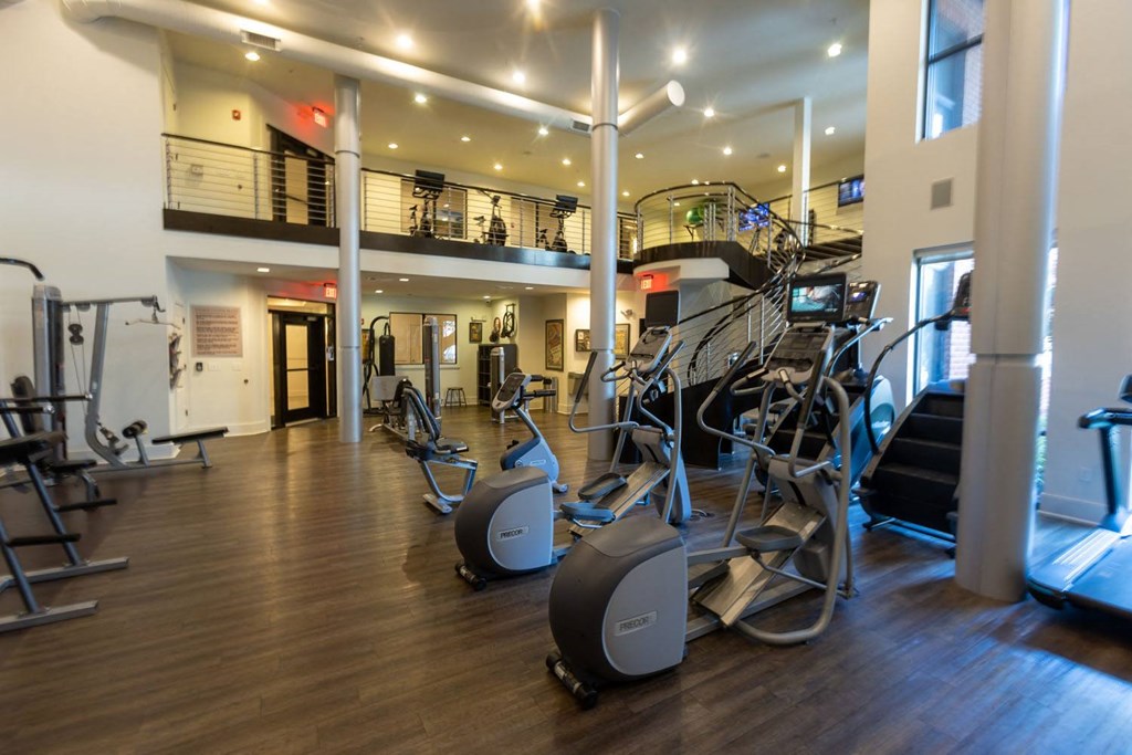 a gym with cardio equipment and weights on a wooden floor