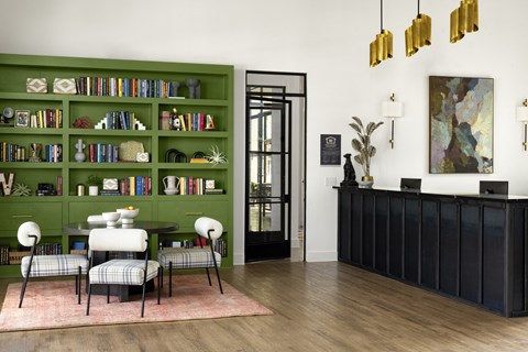 a living room with a green book shelf and a table and chairs