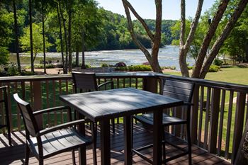 a patio with a table and chairs on a deck overlooking a river