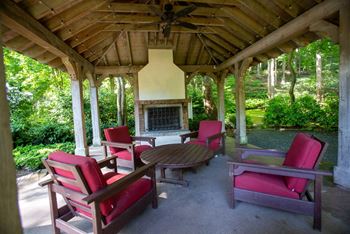 a covered patio with rocking chairs and a fireplace