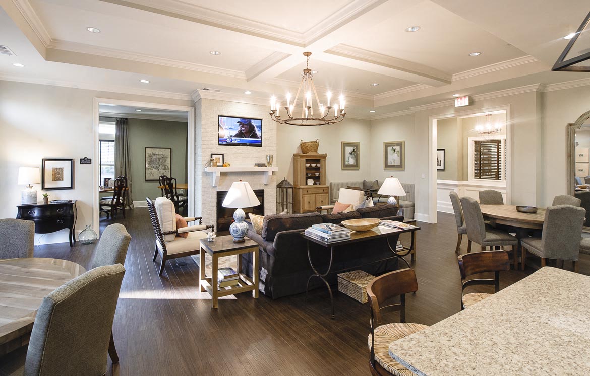 A well-lit, spacious living room with a variety of seating options and a chandelier.
