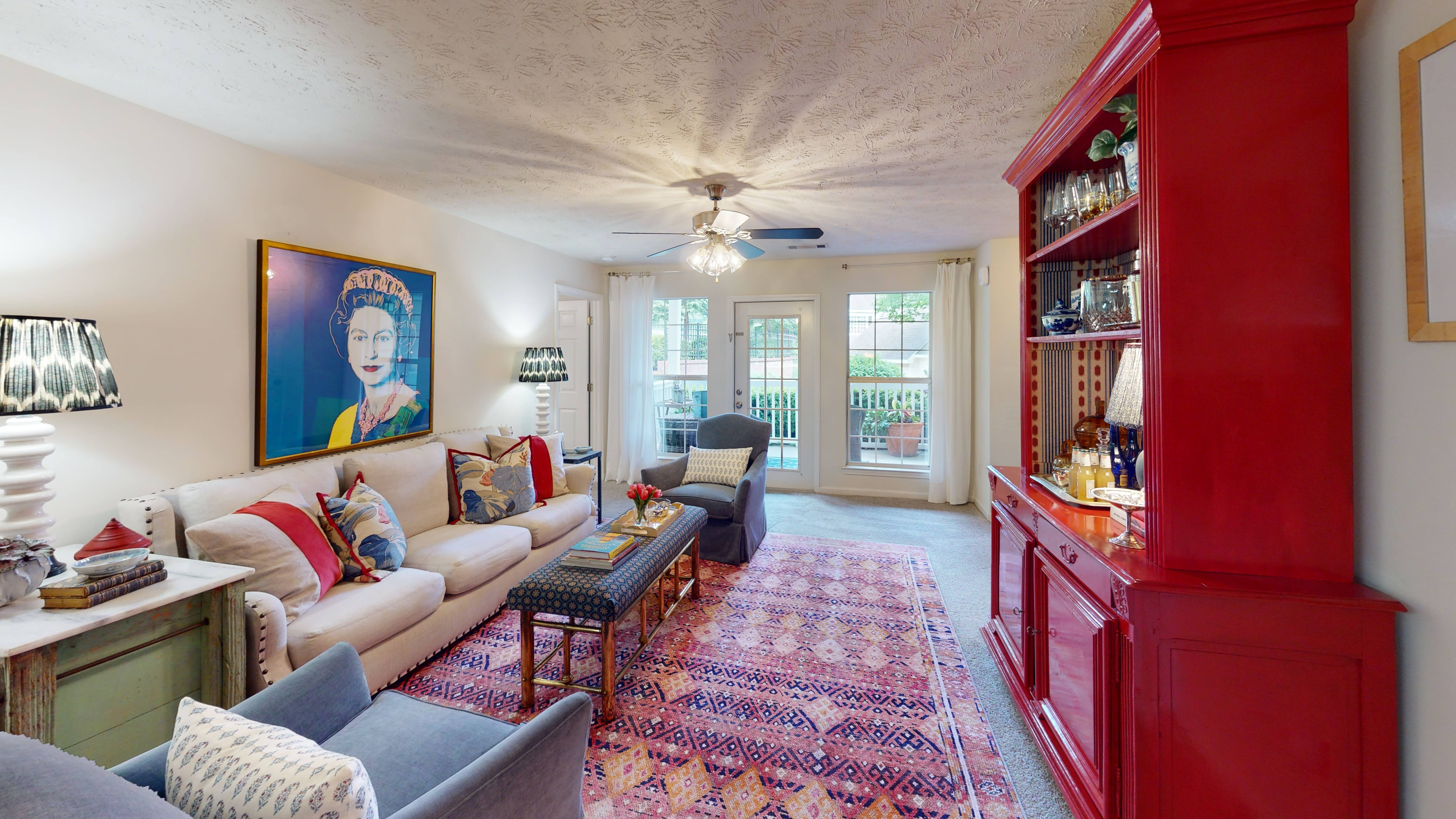 A living room with a red bookcase and a painting of a woman on the wall.