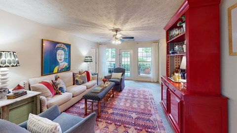 A living room with a red bookcase and a painting of a woman on the wall.