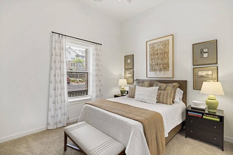 A bedroom with a large bed and a window with curtains.