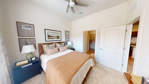 A bedroom with a bed, nightstand, and a ceiling fan.