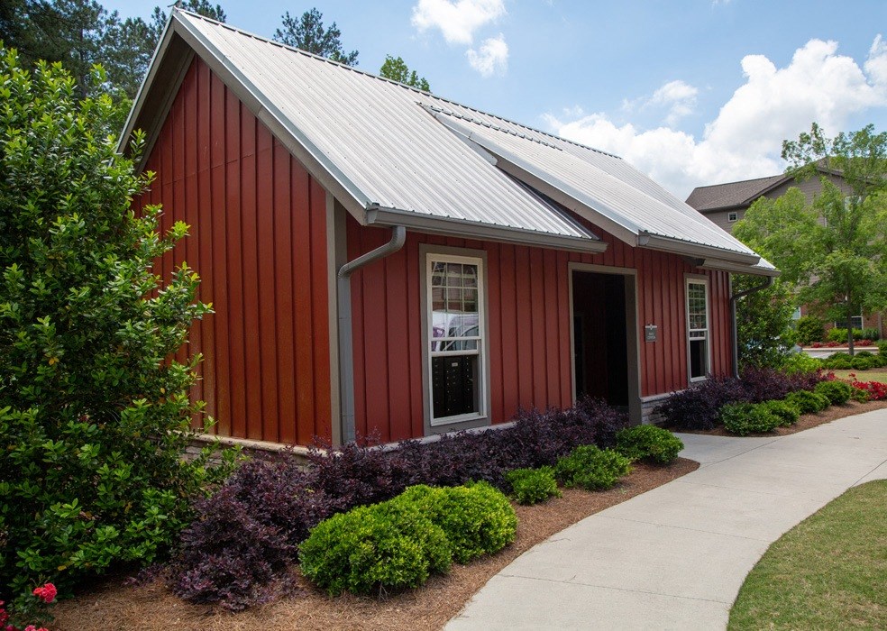 a red building with a metal roof and a sidewalk in front of it