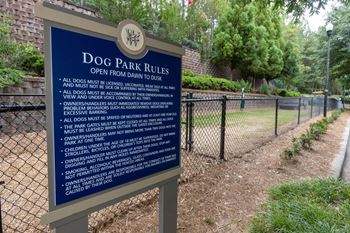 a sign for dog park rules in front of a fence