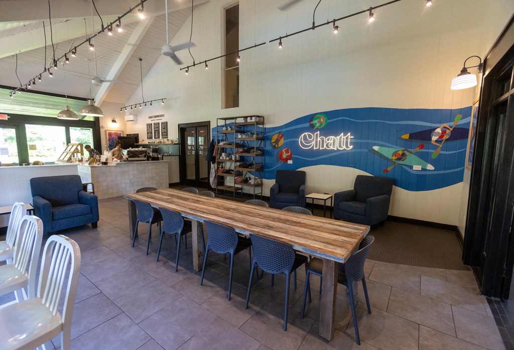 a dining area with a long wooden table with blue chairs and a large mural on the wall