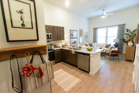 A kitchen with a white counter top and wooden floors.