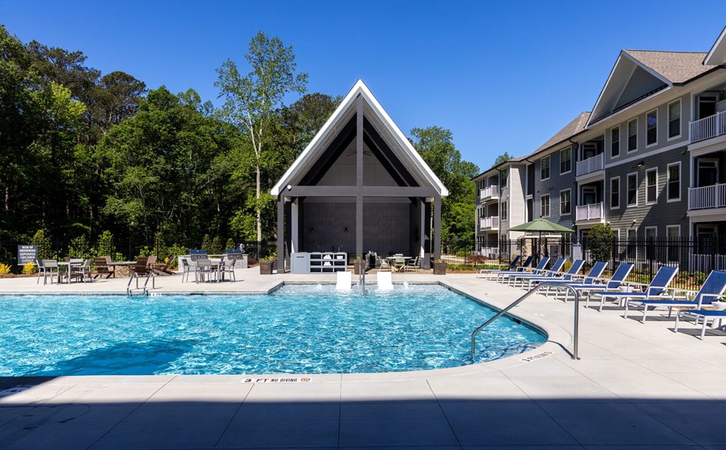 a swimming pool with lounge chairs and umbrellas in front of a building  at Walton Fayetteville, Georgia, 30214
