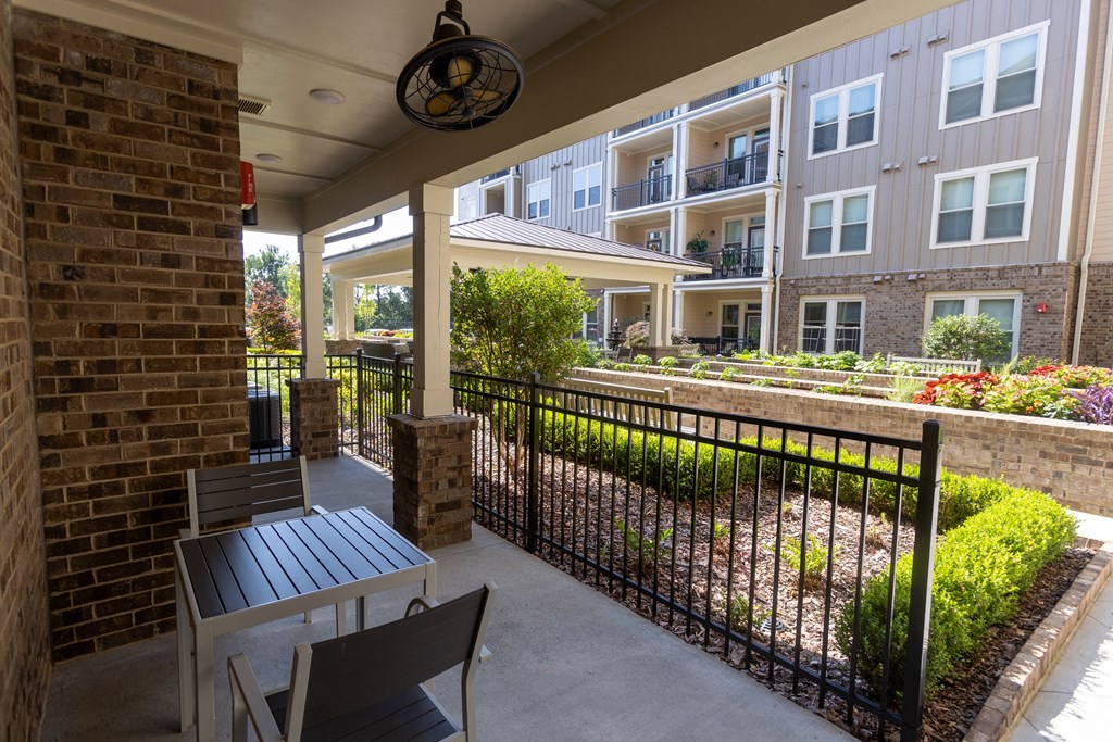 a patio with a table and two chairs and an apartment building in the background