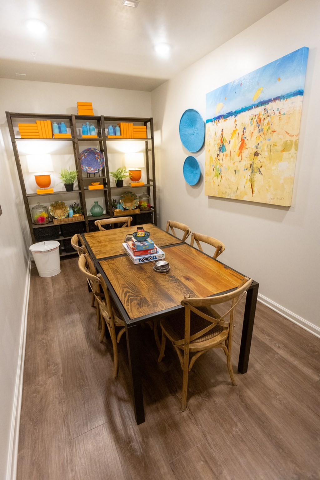 a dining area with a wooden table and chairs and a large painting on the wall