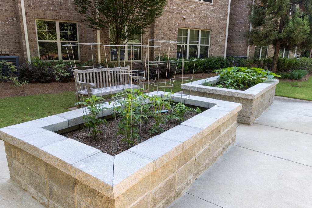 a garden with a bench in front of a brick building