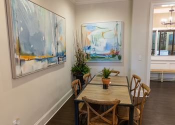 a dining room with paintings on the wall and a table with chairs