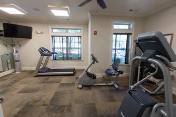a gym with cardio machines and a tv