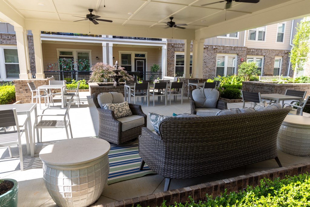 a patio with couches chairs and tables in front of a building