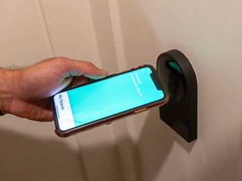 a hand holding a smartphone that is plugged into a door handle