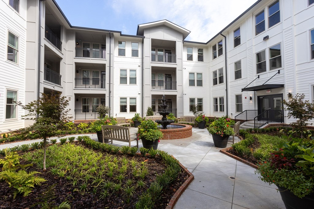 a courtyard with a firepit and benches in front of an apartment building