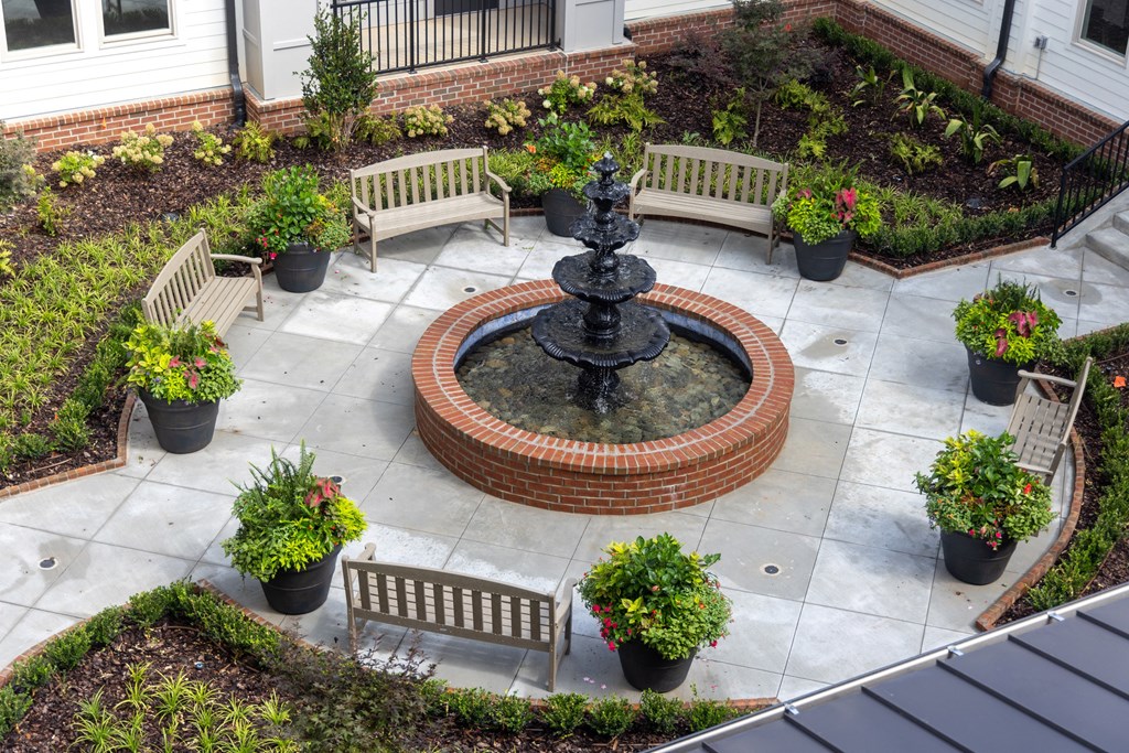 a fountain sits in the middle of a courtyard with benches