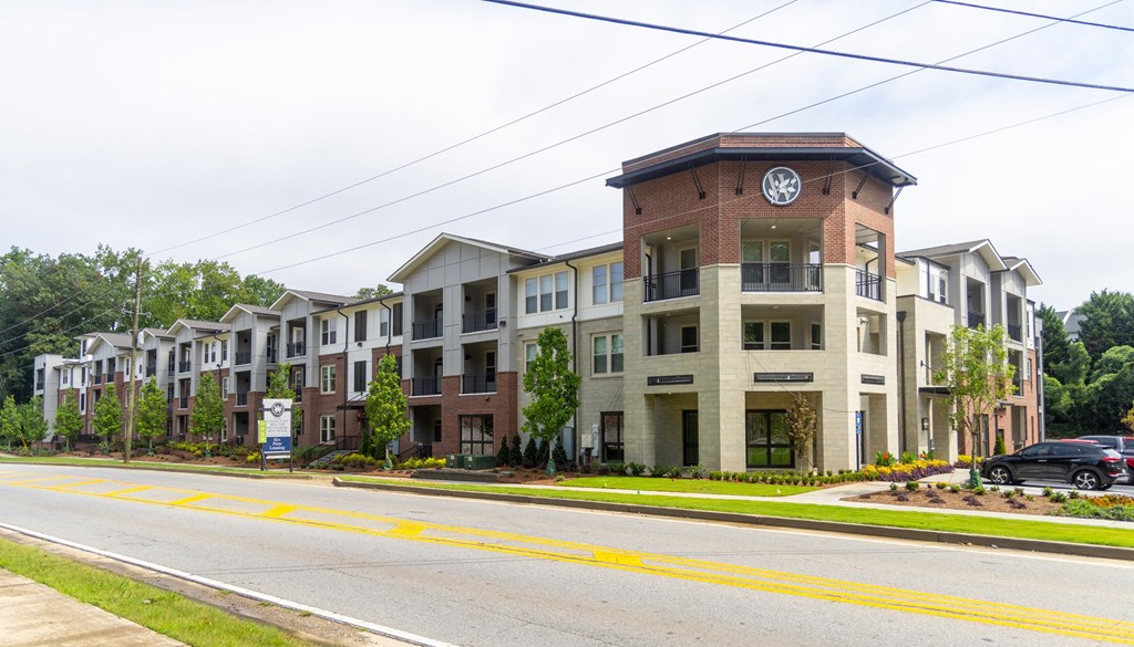a row of apartment buildings with a clock tower in the middle of a street