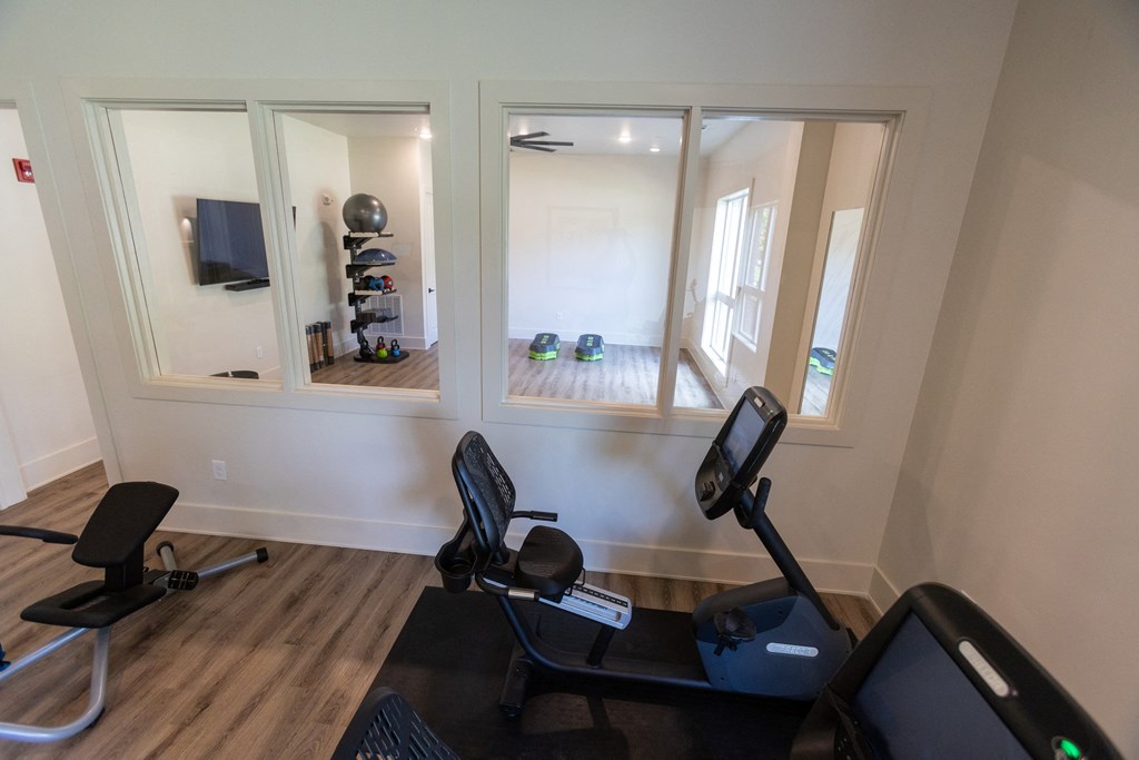 a home gym with three windows and a tv in the background