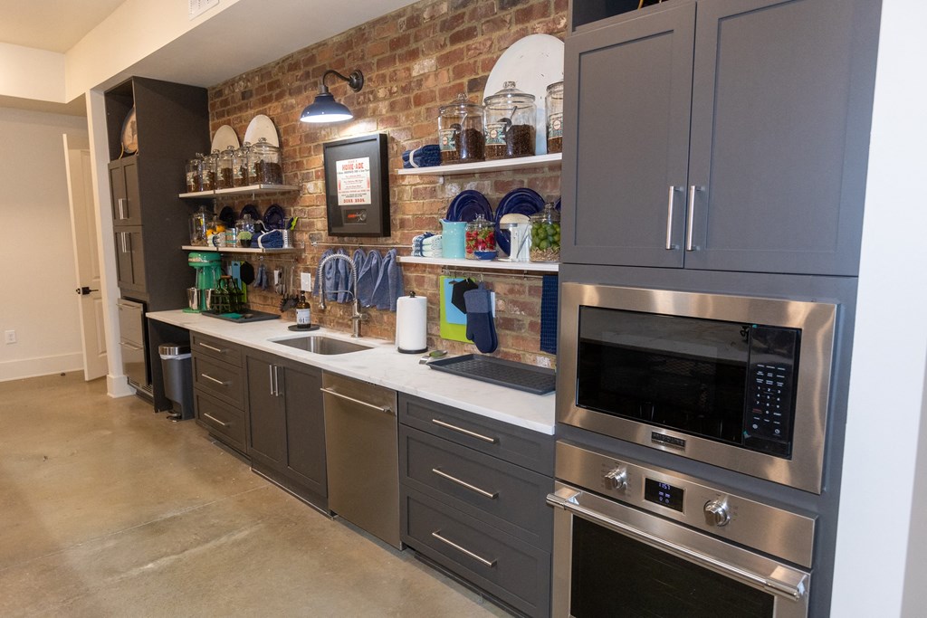 a kitchen with gray cabinets and a brick wall