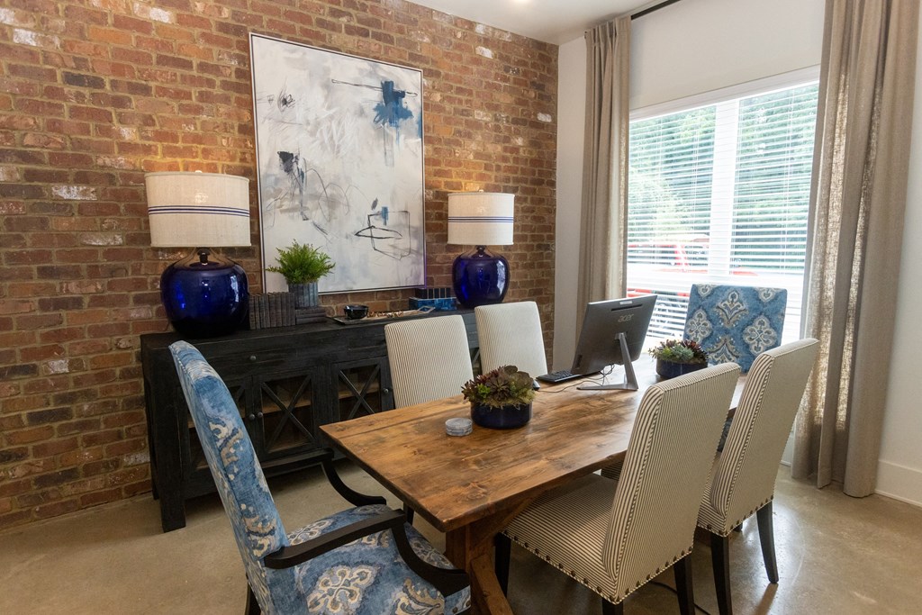 a dining room with brick walls and a wooden table with white chairs and blue upholstery