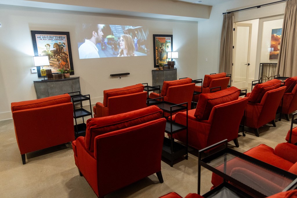 a room with red chairs and a large screen on the wall