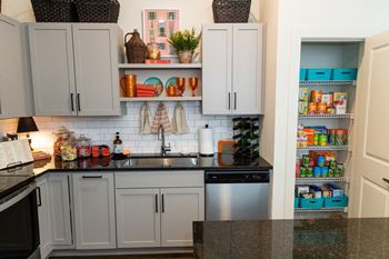 a kitchen with gray cabinets and black countertops