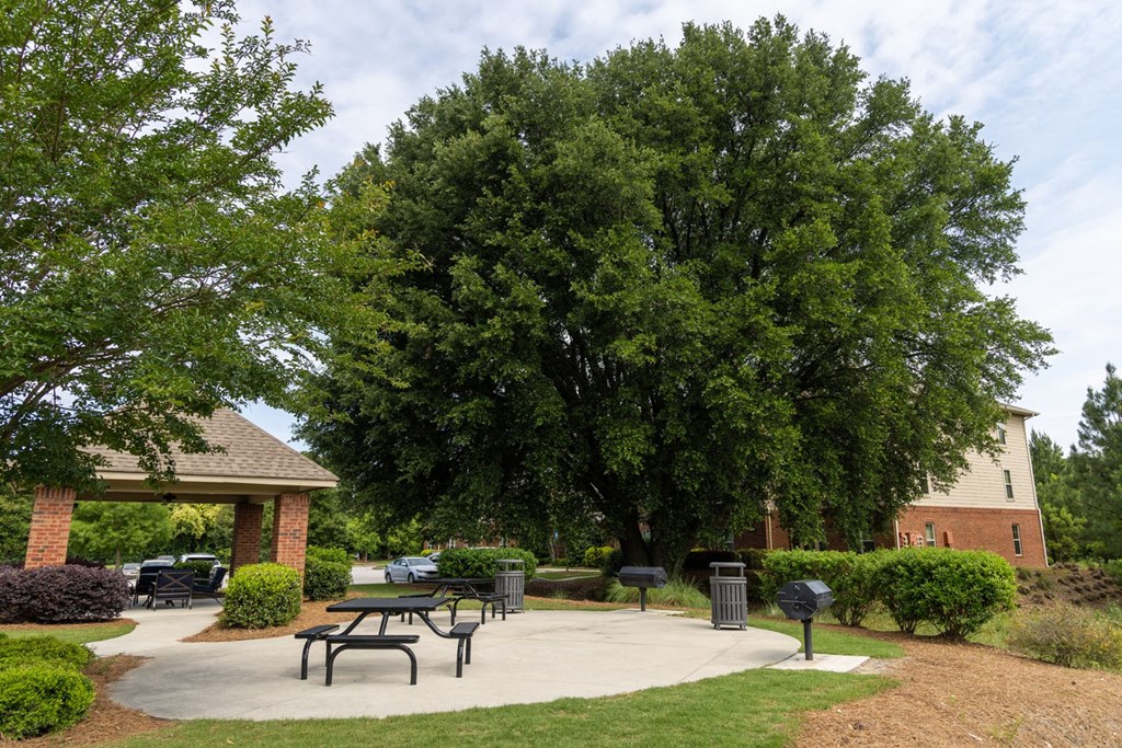 a patio with a picnic table and barbecue grill in front of a brick building