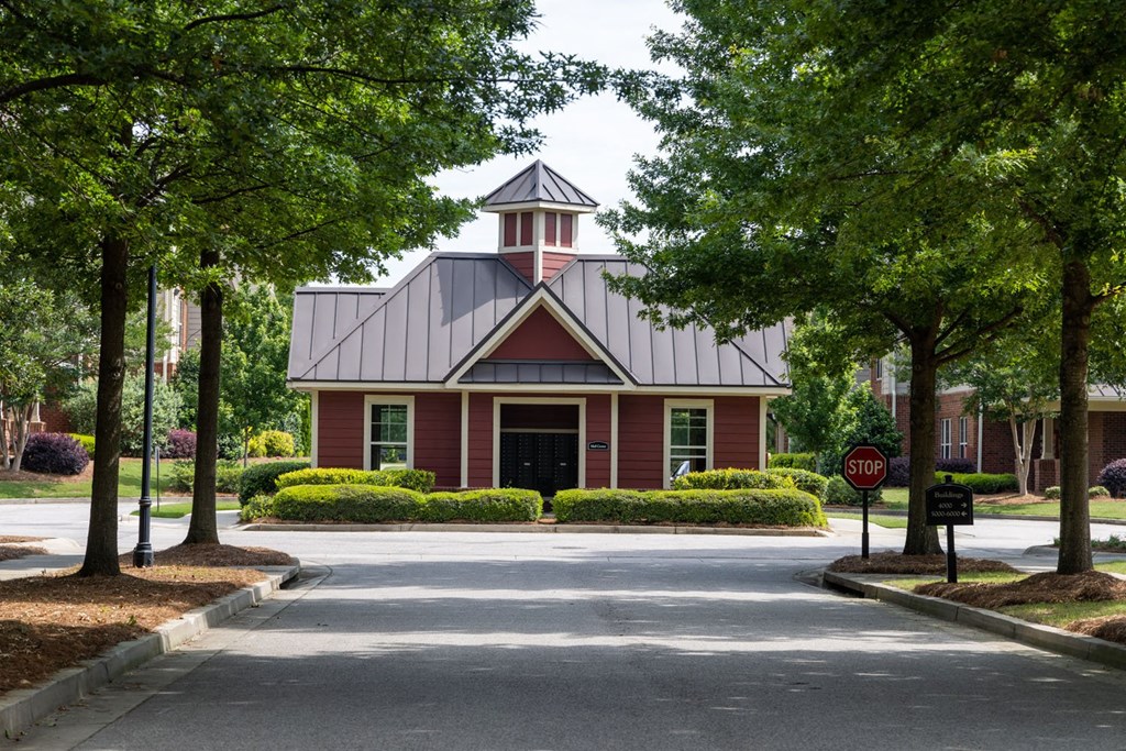 a red building with a grey roof and a stop sign in front of it