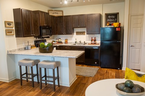 a kitchen with black appliances and a counter with two stools