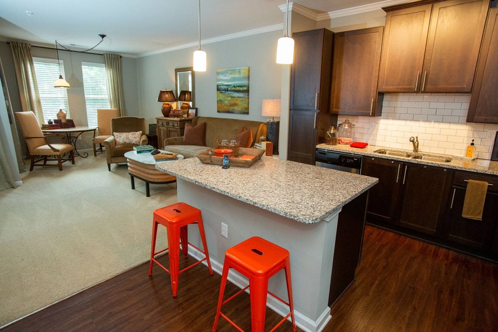 a kitchen and living room with red stools and a granite counter top
