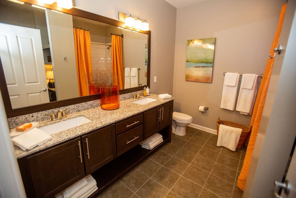 a bathroom with two sinks and a toilet and a large mirror