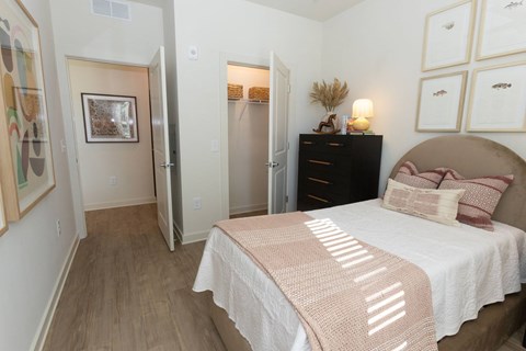 A bedroom with a bed, dresser, and a painting on the wall.