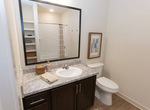A bathroom with a white toilet, sink, and brown cabinets.