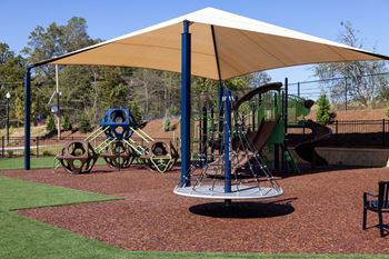 A playground with a swing set and a blue and green slide.