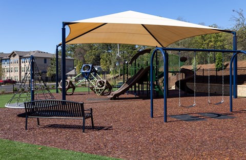 A playground with a swing set and a bench.