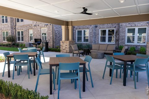 A patio with blue chairs and a table.