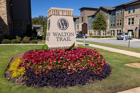 A flower bed in front of a Walton Trail sign.