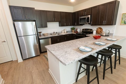 A kitchen with a marble countertop and black bar stools.